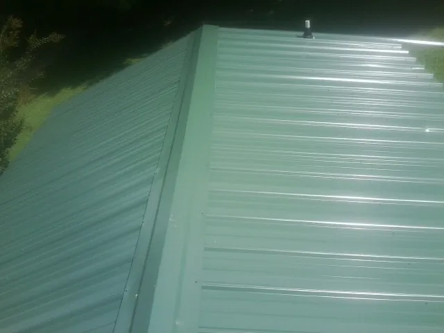 New green metal panels meeting at the ridge of a roof — Flat Roof Repair work by our crew in West Wendover