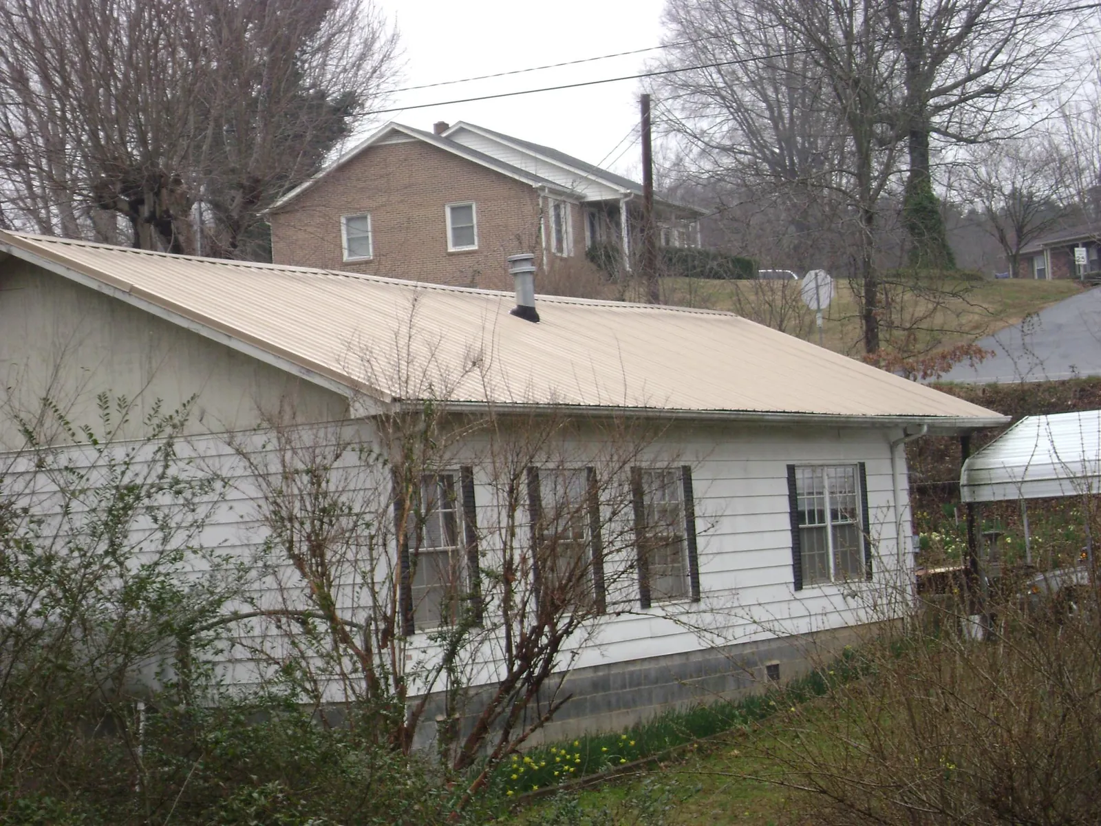Tan metal roof on a white sided house set into a hillside — Commercial Roofing by Roofing Brothers in West Wendover