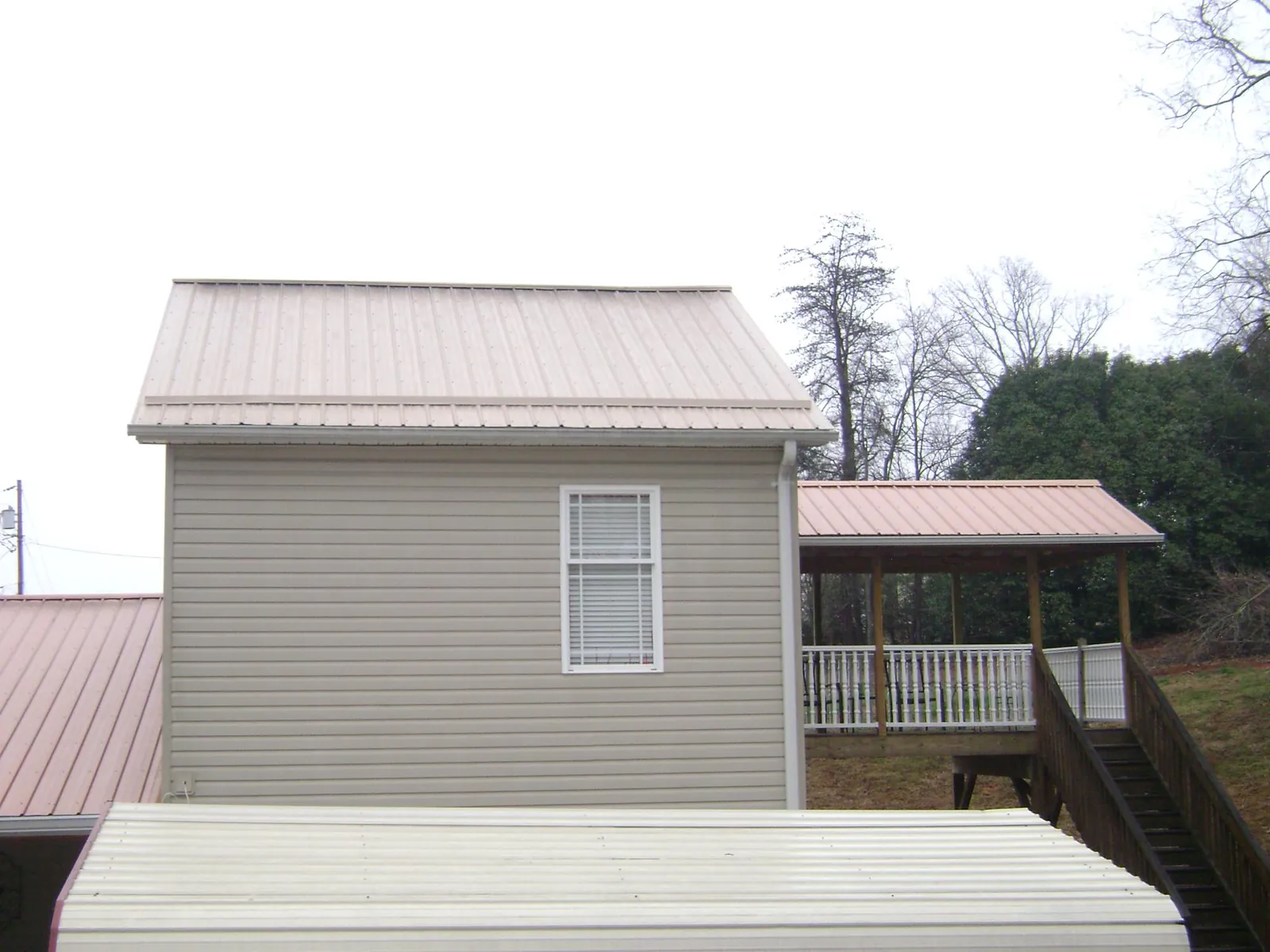 Tan metal roofs on a two story addition and attached porch, from a Roof Replacement job in West Wendover